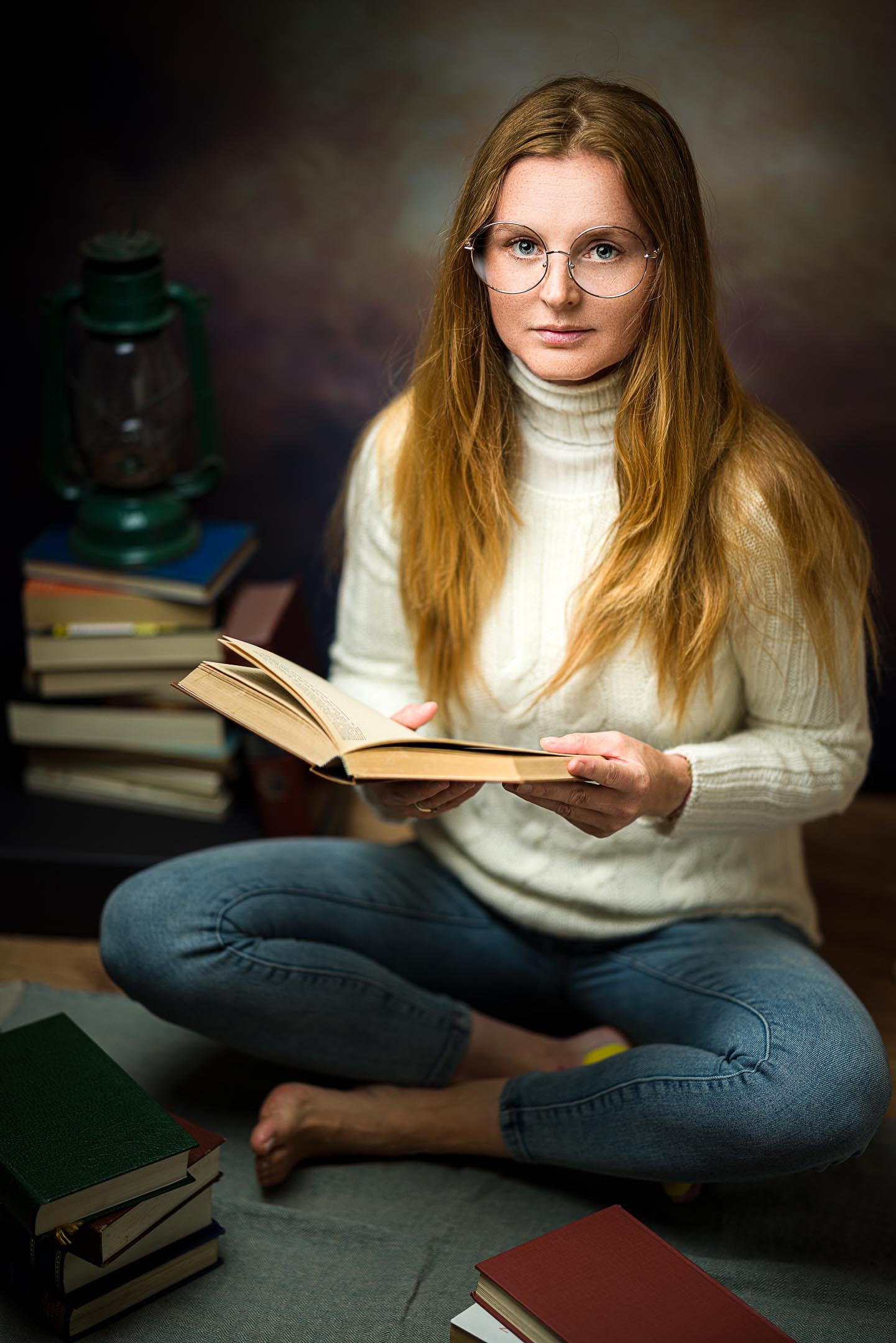 Considered studio portrait, woman reading by lamp light, illustrating a light-first photography style