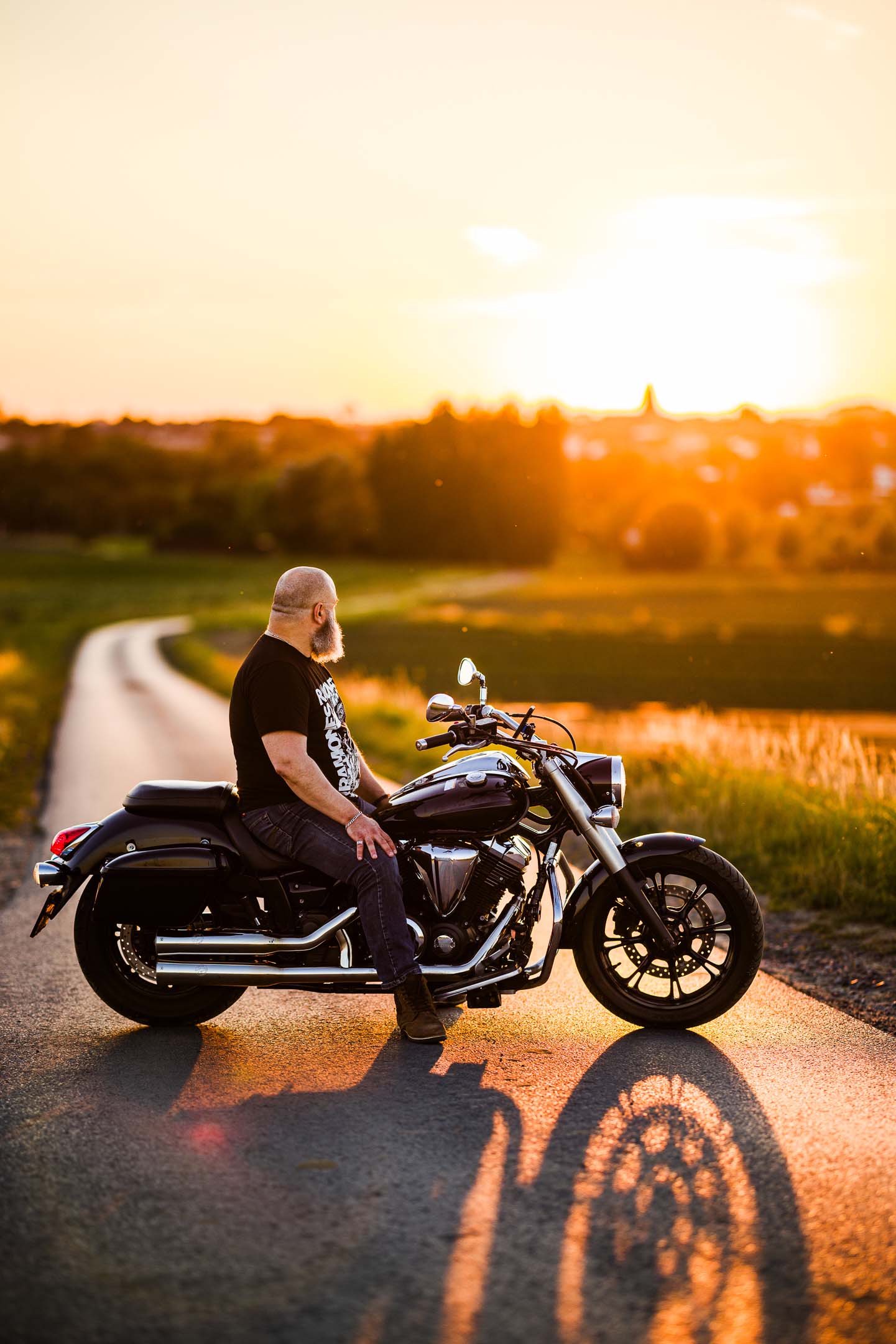 On-location portrait at golden hour, man with motorcycle at sunset
